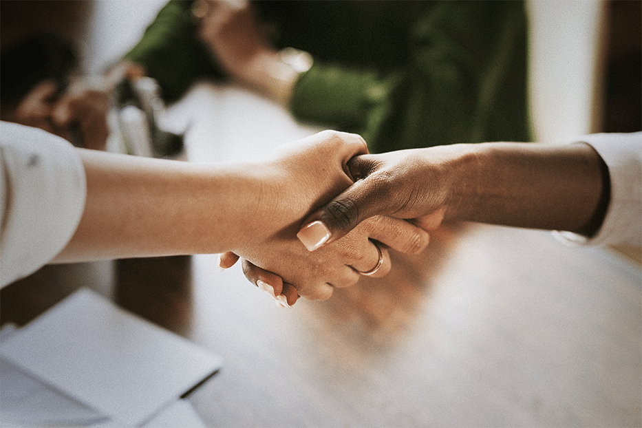 A handshake over a desk to seal a cayman real estate deal.