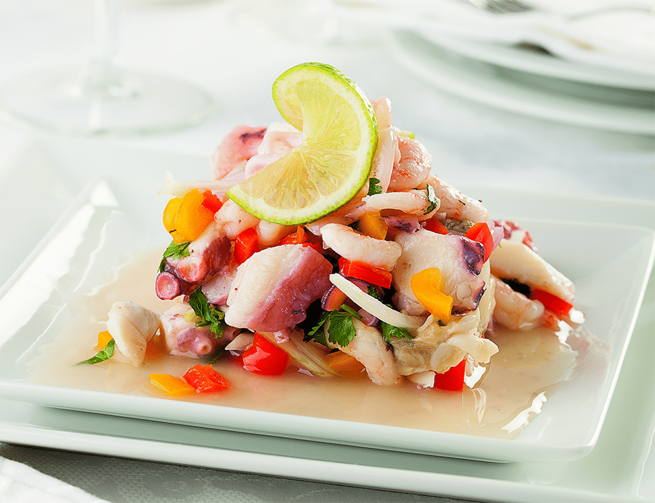 A plate of seafood ceviche with a slice of lime atop.