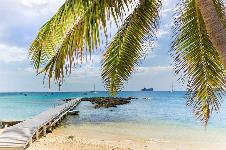 View of cruise ships from the beach out to sea along a jetty in Grand Cayman