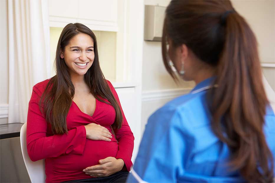 Pregnant girl in consultation with doctor in medical facility.