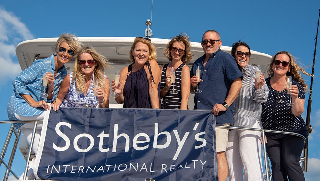 Cayman Islands Sotheby's International Realty team on the back of a boat on the Caribbean Sea.