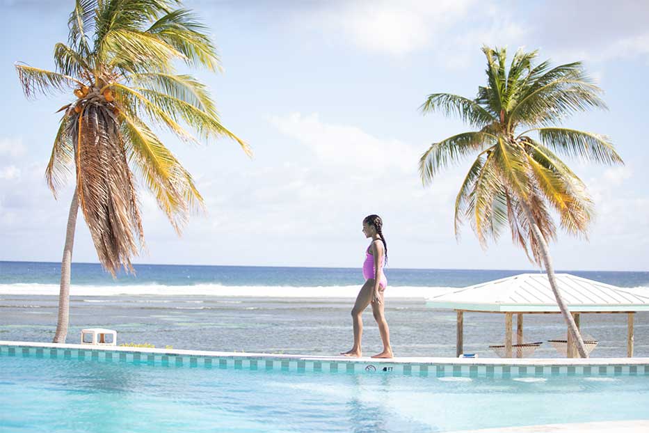 Girl walking alongside a beachfront pool in the Cayman Islands