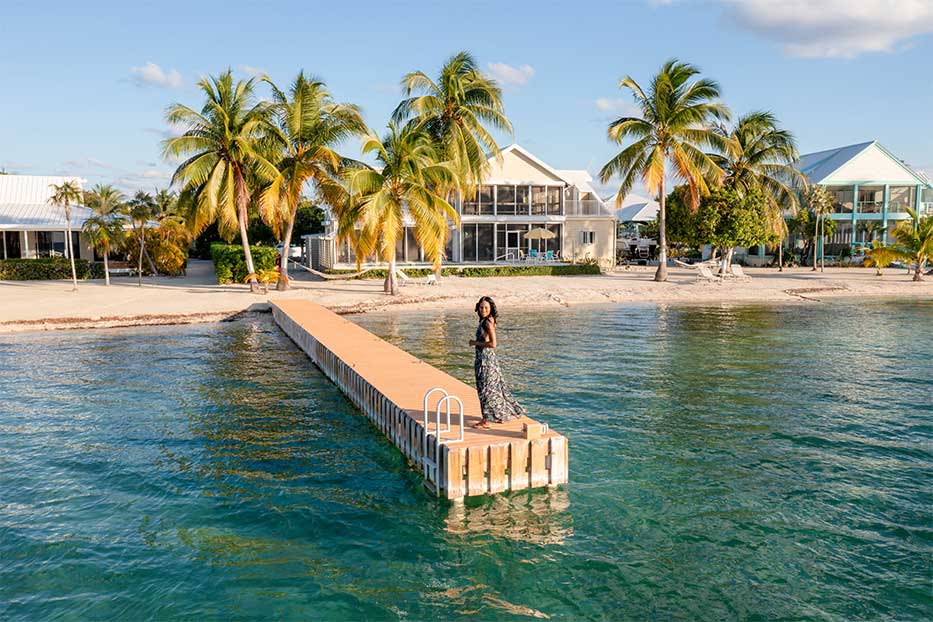 Views of woman standing on boat dock in front of a beach home in Cayman Kai, Grand Cayman