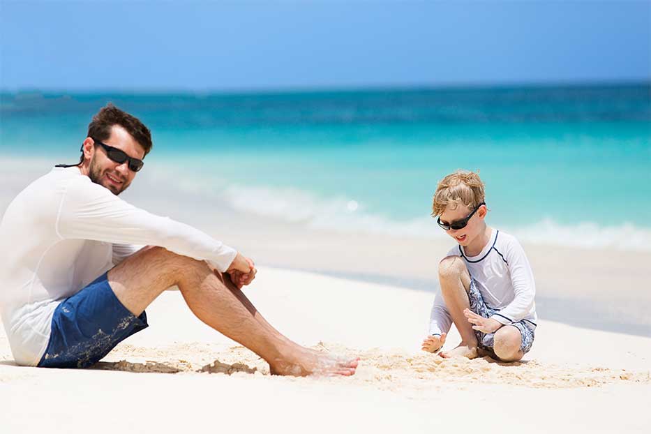 Father and son sitting on beach in the Cayman Islands