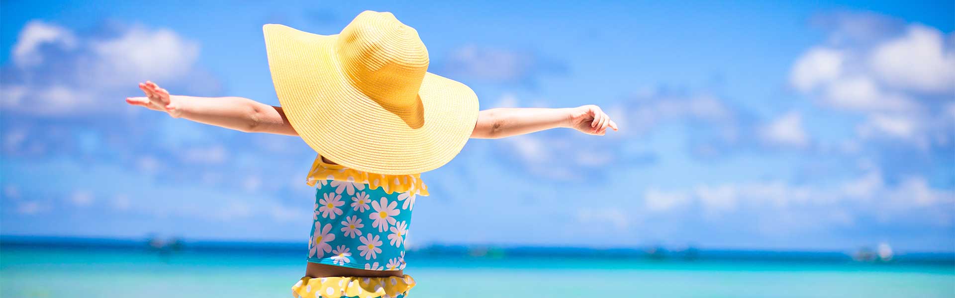 A young girl with arms stretched out on beach in Cayman Islands