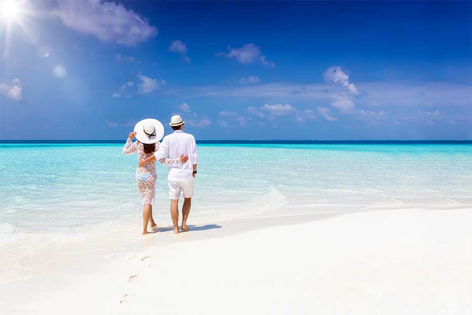 Couple walking along the white sand of Seven Mile Beach