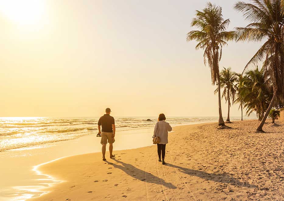 Couple walking along the beach at sunset, Cayman Islands