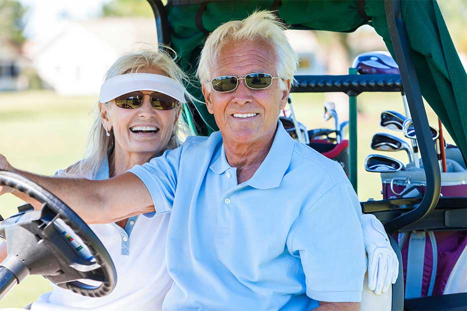 Couple enjoying retirement and a game of golf, smiling from golf cart, Grand Cayman