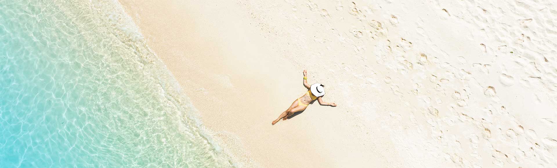 Woman laying on deserted Seven Mile Beach, Cayman Islands