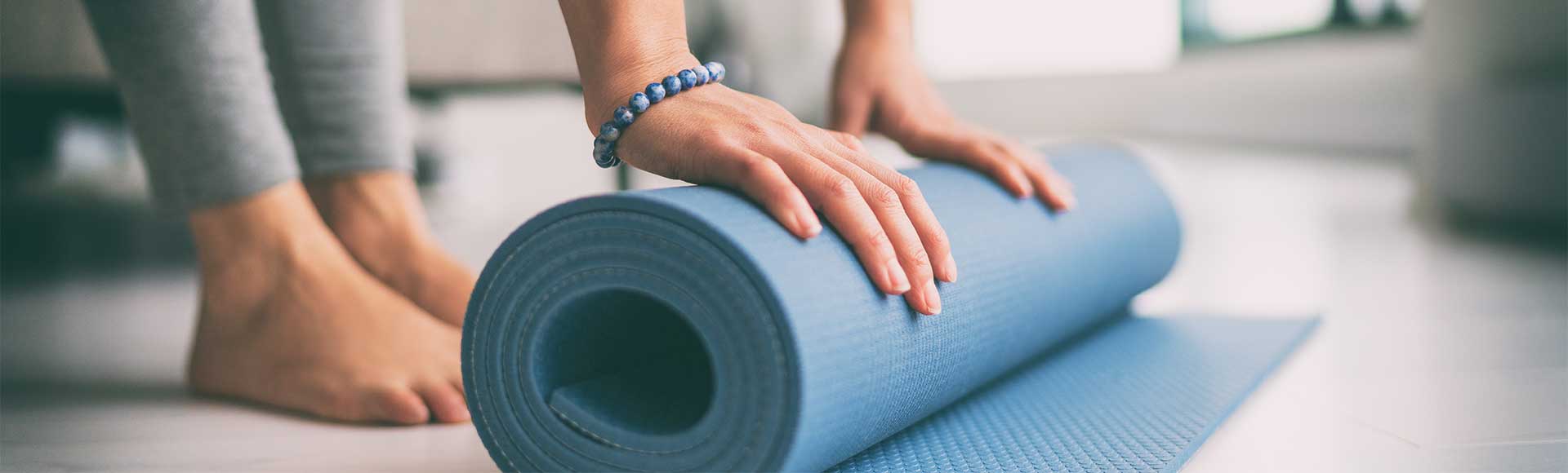 Close up of woman rolling yoga mat