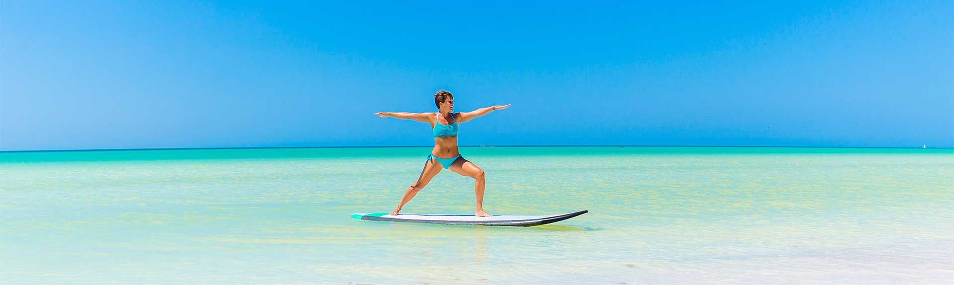 Woman practising yoga on a paddle board in the Cayman Islands