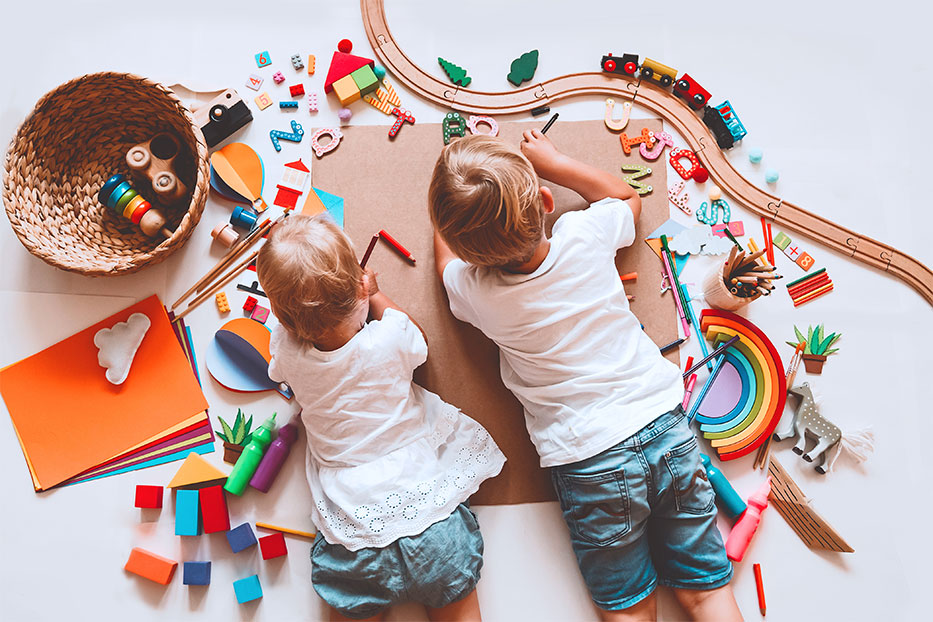 Nursery school children laying on the floor surrounded by learning materials
