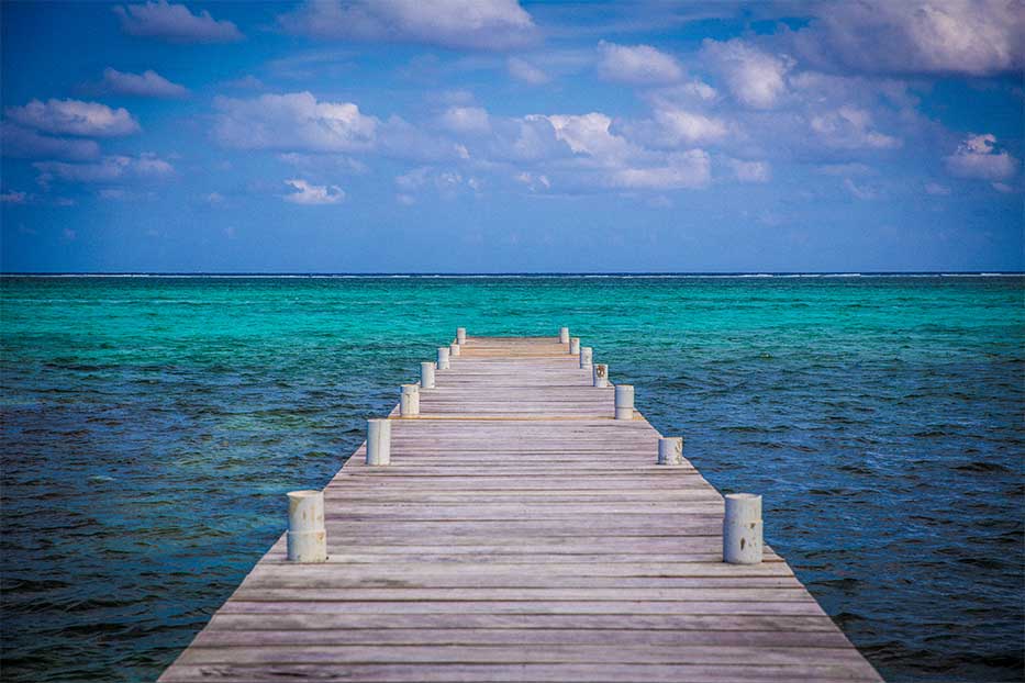Wooden dock leading out to the blue Caribbean Sea.