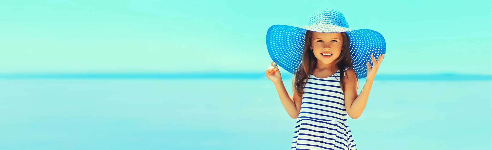 Young girl on beach with a dress and sun hat